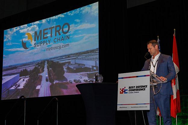 A speaker presenting on stage at the Best Defence Conference