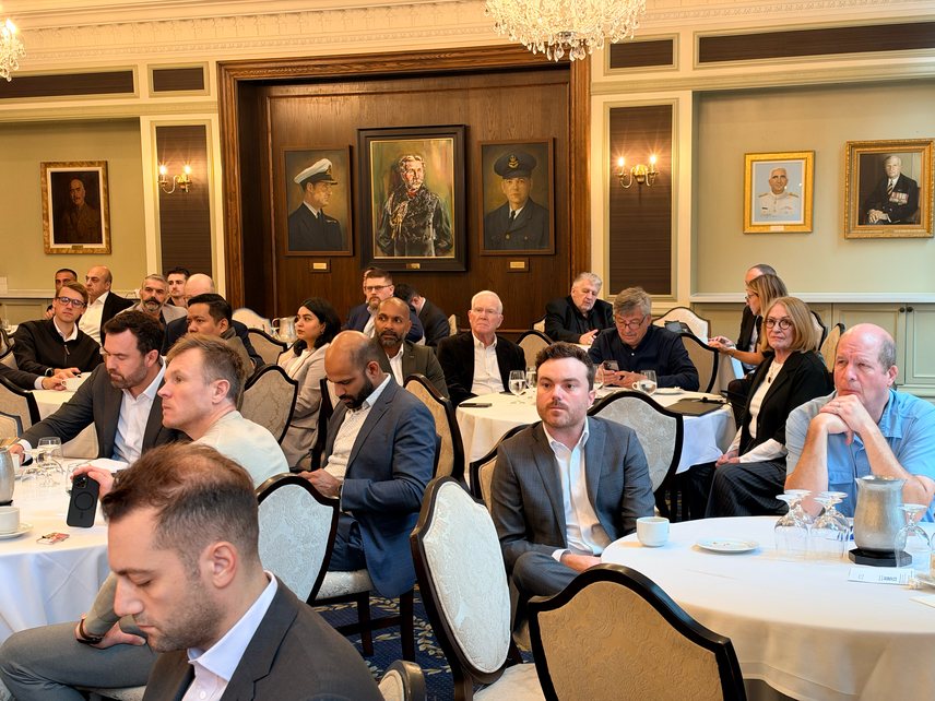 Attendees seated at tables listening to a presentation