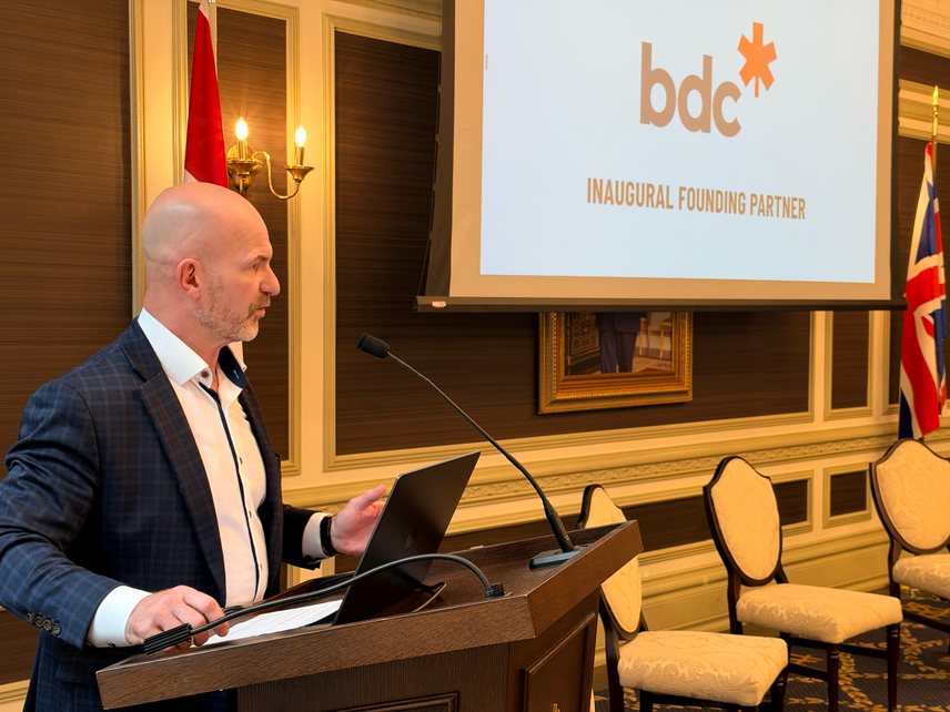 BDC representative speaking at the podium in front of a screen reading BDC Inaugural Founding Partner