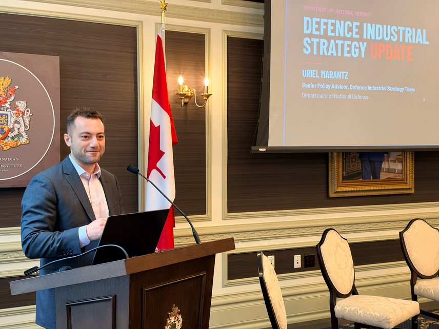 Speaker at the podium in front of a slide titled Defence Industrial Strategy Update