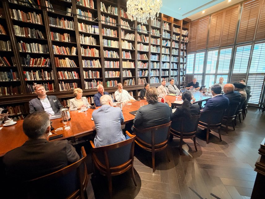 Executives seated around a long table in the RCMI Library, surrounded by bookshelves