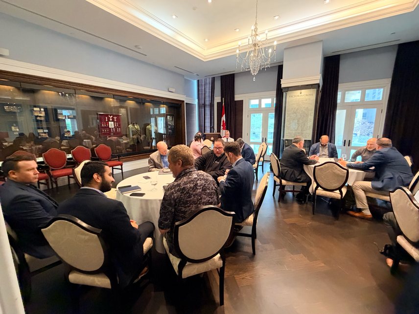 Participants seated at round tables in the Medals Room in front of display cases